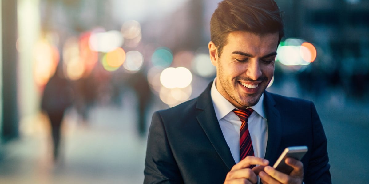 man in suit looking at phone, smiling