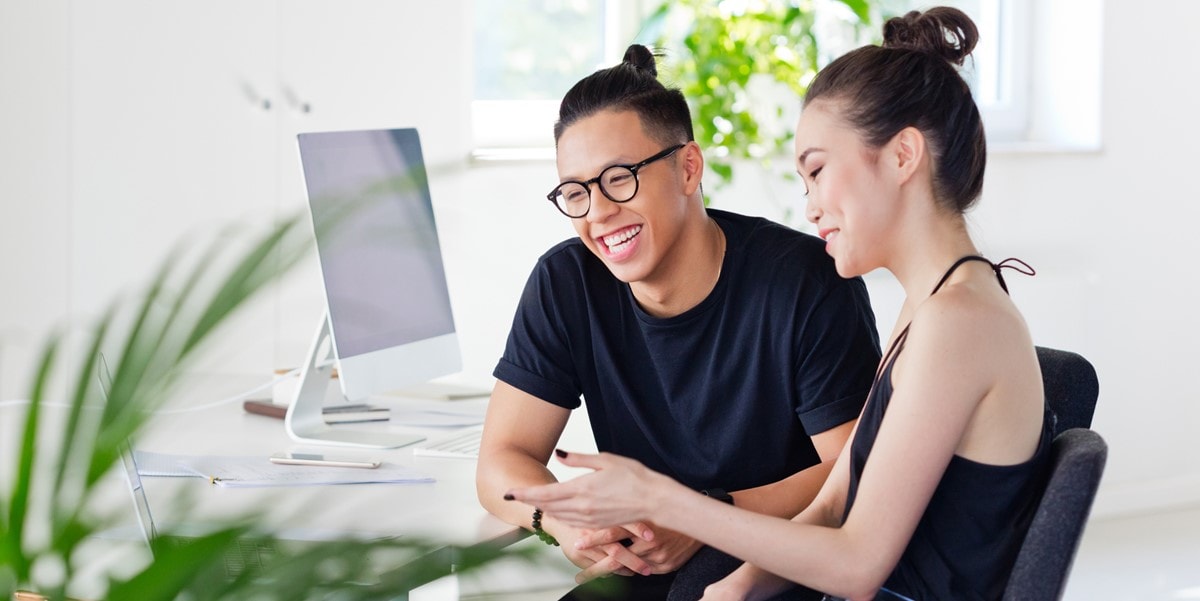 two people in office viewing laptop