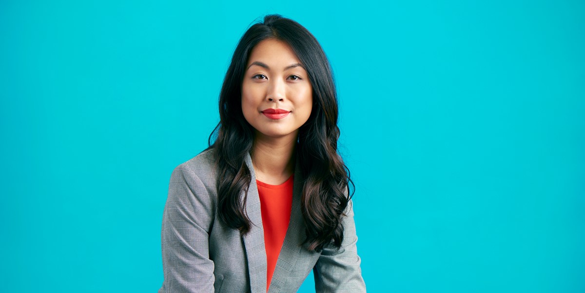 professional woman in grey suit jacket in front of blue background