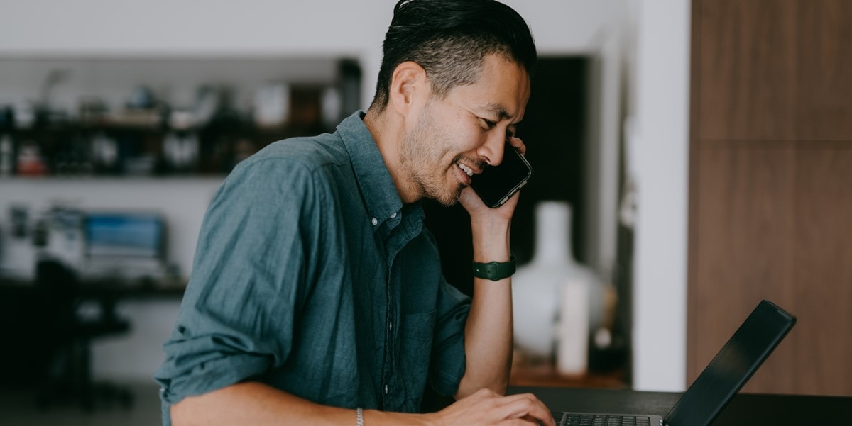 man working at desk, looking at laptop