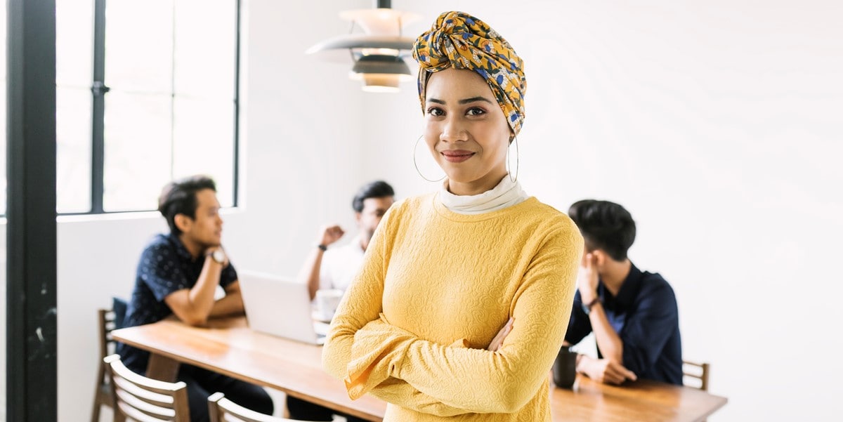 woman in office, group of people sitting at table in the background