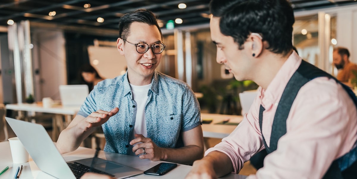 two professionals working at desk, in discussion